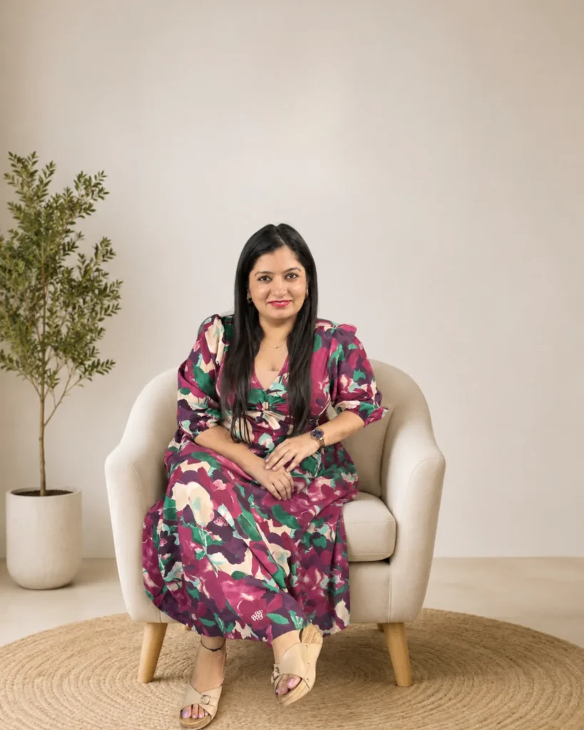 Rupeka seated in a cream armchair, smiling warmly