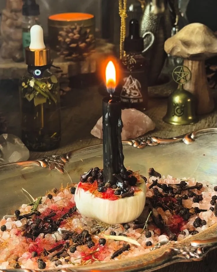 Black candle lit on a dish of salt, cloves and herbs